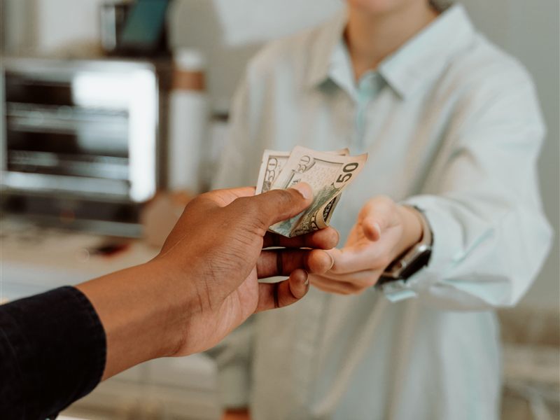 A customer handing cash to a cashier at the counter