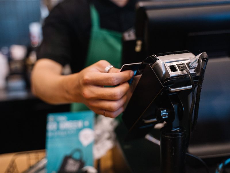 A barista tapping a card on a payment terminal